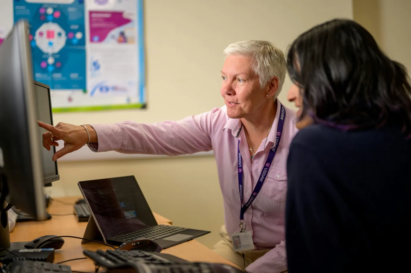 Two colleagues reviewing work together at a computer.